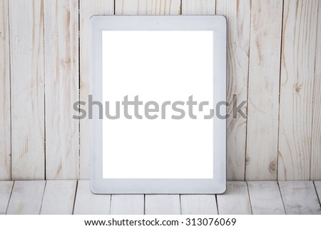 A portrait of a tablet pc on the wall and wooden background, mock up