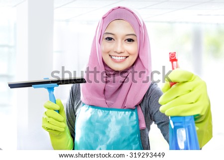 close up portrait of young woman cleaning windows with squeegee and cleaning spray