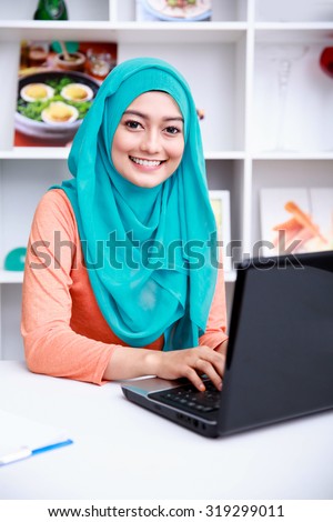 portrait of beautiful young muslim woman working on her laptop at office