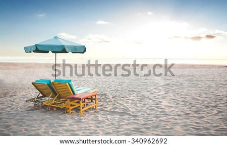 A portrait of a pair of beach chair with umbrella in a seashore