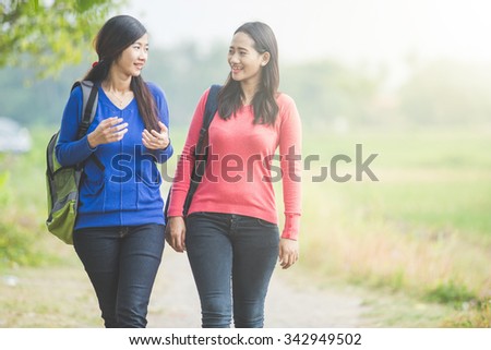 A portrait of two young Asian students chatting while walking together