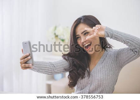 portrait of asian woman take photo of her self using smart phone camera