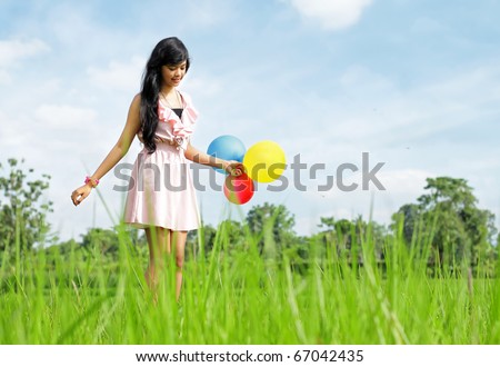 Beautiful girl holding a bunch of colorful balloons in the beautiful nature