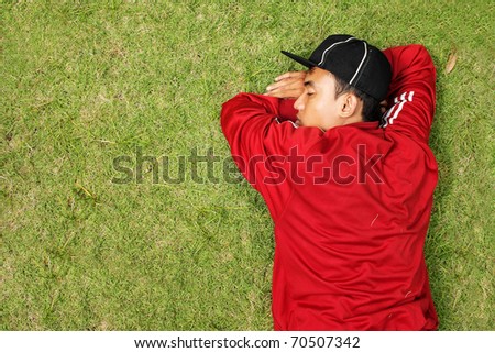 young man wearing red jacket sleeping on the grass