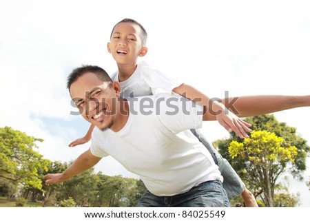 Portrait of father giving his son piggyback ride against sky