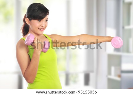 Portrait of pretty young woman using dumbbells during exercising