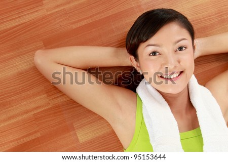 Portrait of gorgeous young female smiling while lying on gym floor