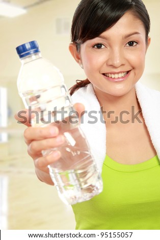 Portrait of healthy fitness woman holding a bottle of water in the gym