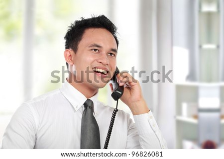 Handsome business man calling while working at the office