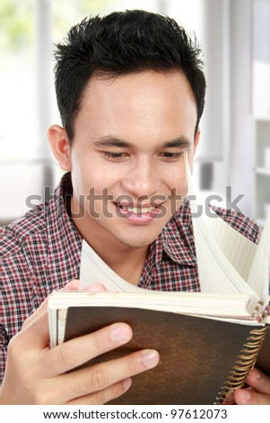 close up portrait of young asian male reading a book