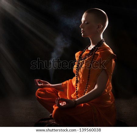 The young woman in orange robers in meditation