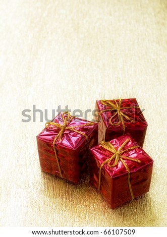Three red gift boxes on a golden background with free space for text