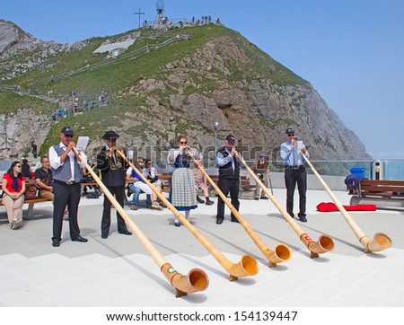 MOUNT PILATUS - JULY 13: Unidentified people playing traditional swiss music with alphorns on July 13, 2013 on the top of Pilatus, Switzerland. Alphorn is traditional music instrument of Switzerland.