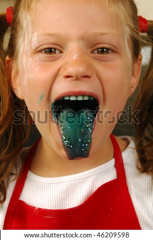A girl sticks her tongue out is colored with green food coloring