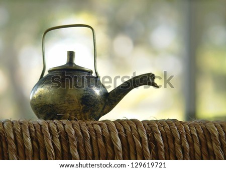 still life with a blurred background, tea outdoors, a small copper kettle standing on the surface of the woven