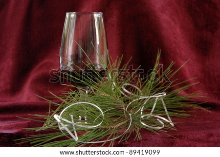 The holiday, New Year, pine branch, streamer, glass with wine on a red background
