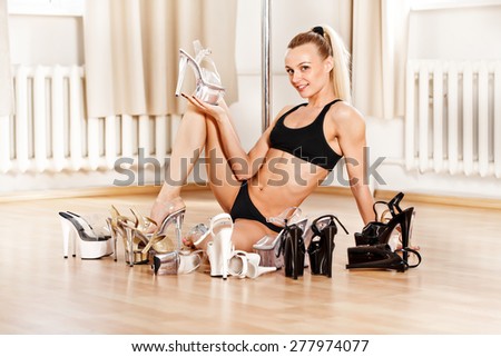 Young slim pole dance woman choosing shoes for strip tease