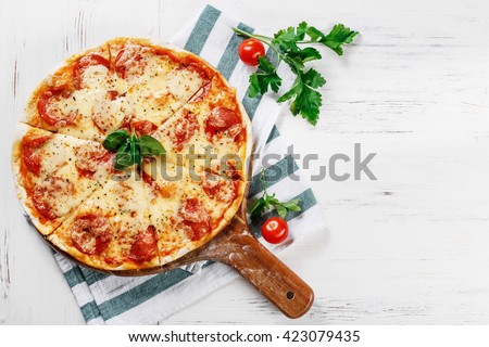 Hot true PEPPERONI ITALIAN PIZZA with salami and cheese. TOP VIEW Tasty traditional pepperoni pizza on board on white wooden table with decoration. Copy space for your logo. Ideal for commercial