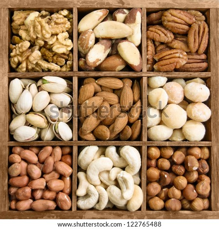 Assorted nuts in a wooden box (from top left: walnut, brazil nut, pecan, pistachios, almond, macadamia, peanut, cashew, hazelnut)