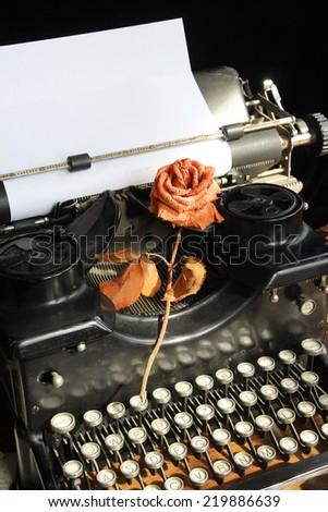 Classic type writer with blank paper and a withered rose