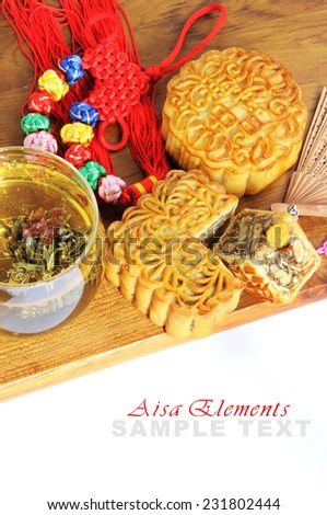 Asia tea time elements: flower tea, moon cake, lucky knot, sandalwood fan on a wooden board