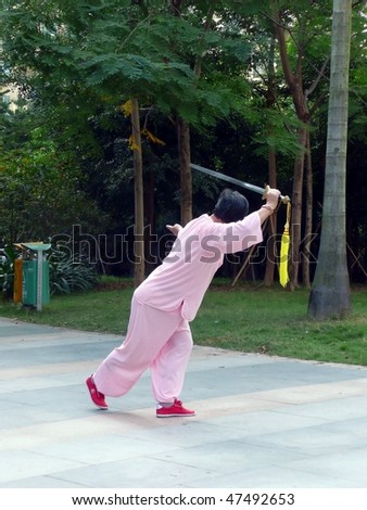 SHENZHEN, CHINA - OCT  28: a retired Chinese woman exercises by doing a sword dance in a public garden, it is her daily morning exercise.  October 28 in Shenzhen, China.