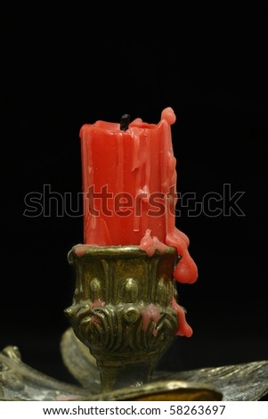macro shot of a burnt red candle on the candle holder against black ground