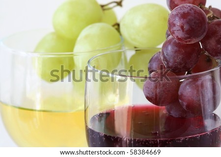 Green and red grapes on the white and red wine glasses (main focus on red grapes)