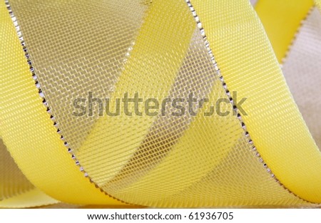 Macro shot of a yellow ribbon with golden textile background