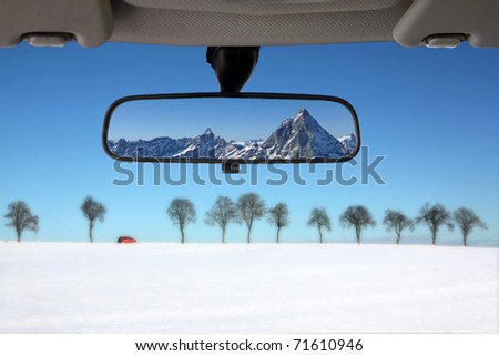 Winter landscape reflected in the car rear mirror