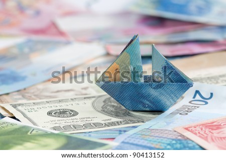 Swiss france folded as boat on world currencies - symbol of strong Swiss francs and other currencies with sinking values.