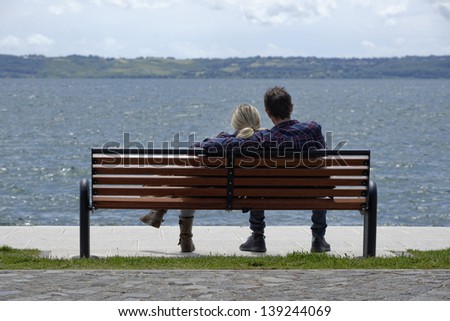 Italy, Bracciano lake (Rome), young couple relaxing on a bench