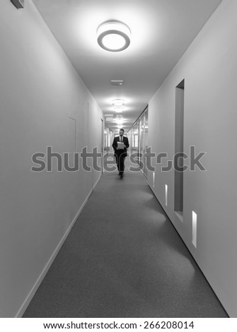 Italy, man walking in a corporate building corridor