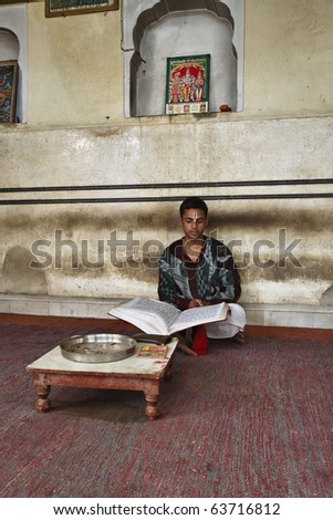 India, Rajasthan, Jaipur, an indian boy reads a religious book in an hindu temple near Sisodia Rani Ka Bagh Palace