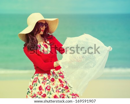 beautiful lady in red with umbrella near the sea in retro style