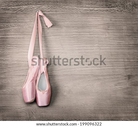 New pink ballet shoes hanging on wooden background.Vintage style.