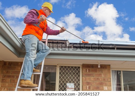 experienced worker cleaning solar panels on house roof