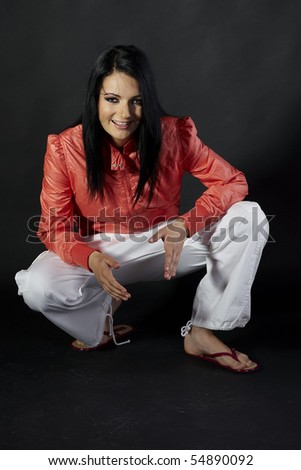 Sexy young slim brunette wearing orange jacket, white ducks and flip-flops (Isolated on the black background)