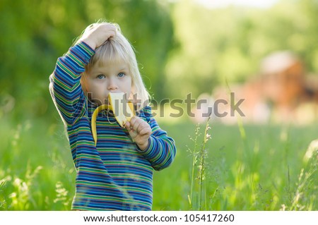 Adorable baby eat banana stay in high grass in park