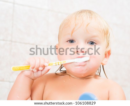 Adorable baby brushing teeth staying in bath
