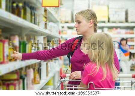 Mother and daughter shopping in oil section in supermarket