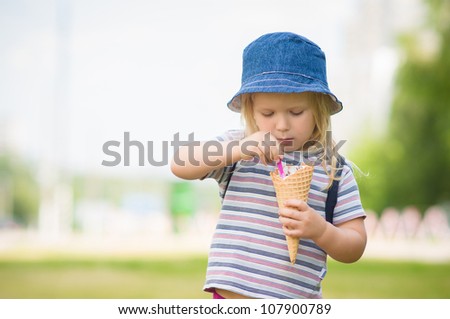 Adorable girl in blue hat eat ice cream