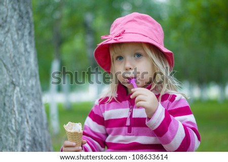 Adorable girl in red hat eat ice cream under trees