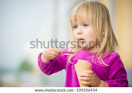 Adorable girl eat ice cream near mall