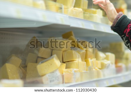 Customer select variety of cheese pieces in supermarket