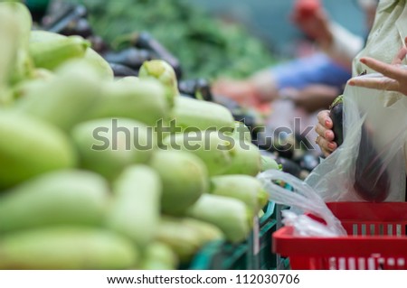 Zucchini in boxes in supermarket. Customers select zucchini