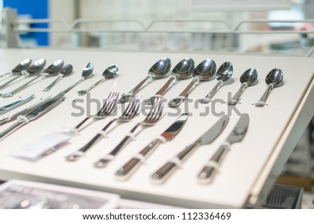 Stands with spoons, knifes and forks on tables in supermarket