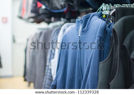 Variety of sweaters and vests on stands in supermarket