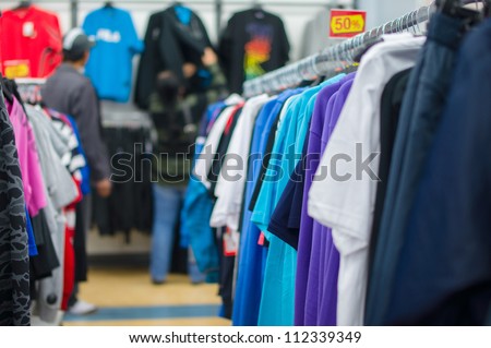 Bright color t-shirts and trousers on stands in supermarket