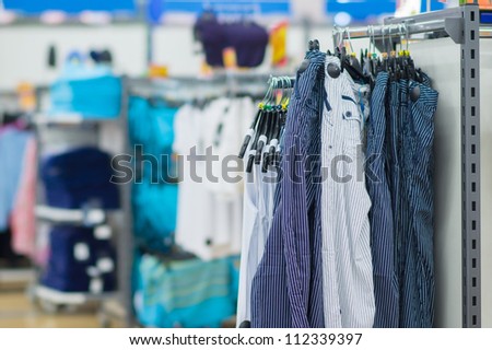Bright trousers with stripes and t-shirts on stands in supermarket